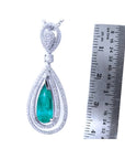 2.13 ct teardrop emerald pendant with double diamond halo in 18K white gold, next to a ruler.