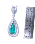 2.13 ct teardrop emerald pendant with double diamond halo in 18K white gold, next to a ruler.