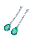 Left profile of a pair of emerald teardrop earrings with diamond accents on a white gold strip