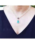 Pear emerald enhancer necklace with halo diamonds on a double strand pearl chain.
