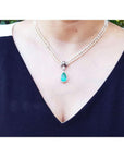 Pear emerald enhancer necklace with halo diamonds on a double strand pearl chain.
