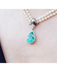 Pear-shaped emerald enhancer necklace with halo diamonds on a double strand pearl chain.