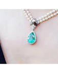Pear-shaped emerald enhancer necklace with halo diamonds on a double strand pearl chain.