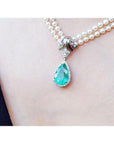 Pear-shaped emerald enhancer necklace with halo diamonds on a double strand pearl chain.