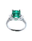 Anillo de compromiso de oro blanco 18k con esmeralda colombiana ovalada y diamantes trapezoide.