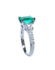Anillo de compromiso de oro blanco 18k con esmeralda colombiana ovalada y diamantes trapezoide.