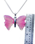Pink natural agate butterfly pendant with silver setting on a silver chain, next to a ruler.