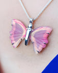 Pink natural agate butterfly pendant on a silver necklace, worn on a blue top.