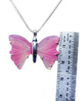 Pink natural agate butterfly pendant with silver setting on a silver chain, next to a ruler.