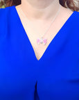 Pink natural agate butterfly pendant on a silver necklace, worn on a blue top.