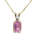 A genuine emerald-cut pink sapphire pendant necklace, featuring an accent natural diamond in a prong setting, crafted in 14k yellow gold.