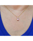 14k gold necklace with a pink genuine sapphire pendant worn by a person in a blue top.