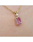 14k yellow gold necklace with a pink sapphire pendant on a skin background.
