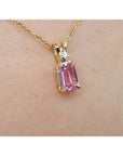 14k yellow gold necklace with a pink sapphire pendant on a skin background.