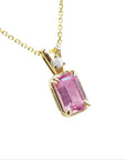 Emerald-cut pink sapphire pendant necklace, with a natural diamond in a prong setting, crafted in 14k yellow gold.