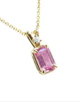 Emerald-cut pink sapphire pendant necklace, with a natural diamond in a prong setting, crafted in 14k yellow gold.