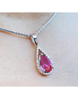 Teardrop-shaped pink sapphire gemstone necklace on a light skin background