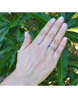 Women's 14k white gold ring with an oval pink sapphire and diamond halo on a hand.