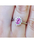 Natural pink sapphire ring for women halo diamond in 14k white gold, on a finger.