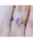 Natural pink sapphire ring for women halo diamond in 14k white gold, on a finger.