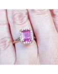 Pink sapphire ring for women emerald-cut halo diamonds 14k yellow gold, o a woman's hand