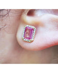 Natural pink sapphire stud earrings halo diamonds 14k yellow gold, worn on an ear.