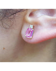 Close-up of a pink sapphire earring worn on an ear.