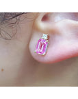 Genuine Pink sapphire stud earrings rectangular emerald cut medium pink color, very brilliant, natural diamonds on top, worn on an ear.