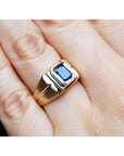 Men's 14k yellow gold pinky ring with a rectangular, medium dark blue sapphire, bezel set.
