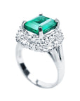 A platinum emerald ring on top and side profile view.