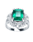 A platinum ring with a colombian emerald and diamond accents on a topside view.