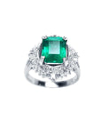 A platinum ring with a colombian emerald and diamond accents on a topside view.