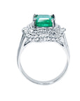 Ring with a natural emerald and diamond accents on a lateral profile view.
