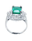 Ring with a colombian emerald and diamond accents on a white background.