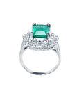 Ring with a colombian emerald and diamond accents on a white background.