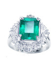 Platinum emerald ring for women and diamond accents on a topside view position.