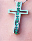 Emerald cross pendant necklace crafted in white gold.