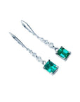14K white gold dangle earrings with emerald-cut Colombian emeralds and diamond accents.