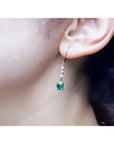 14K white gold dangle earrings with three small diamonds and a square-cut Colombian emerald.