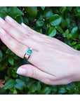 Men's 18K yellow gold ring with a medium bluish-green emerald and two accent diamonds.