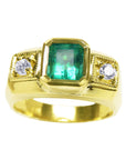 Gold ring for men with a natural emerald and two side diamonds on a topside view.