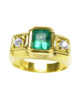 Gold ring for men with a natural emerald and two side diamonds on a topside view.