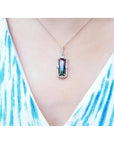 Watermelon tourmaline pendant with diamond halo on an 18K white gold chain, worn on a person.