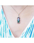 Watermelon tourmaline pendant with diamond halo on an 18K white gold chain, worn on a person.