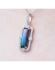 A bicolor tourmaline pendant on a white gold chain against a light pink skin background.