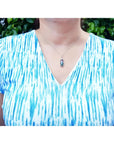 Watermelon tourmaline and diamond pendant on an 18K white gold necklace worn on a person.