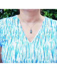 Watermelon tourmaline and diamond pendant on an 18K white gold necklace worn on a person.