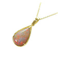 Pear-shaped Australian opal pendant with fiery red/orange hues, set in 14k yellow gold on a delicate chain.