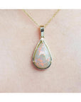Pear-shaped Australian opal pendant with fiery red-orange hues in 14k yellow gold.