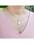 Pear-shaped Australian opal pendant with fiery red-orange hues in 14k yellow gold, worn on a woman.